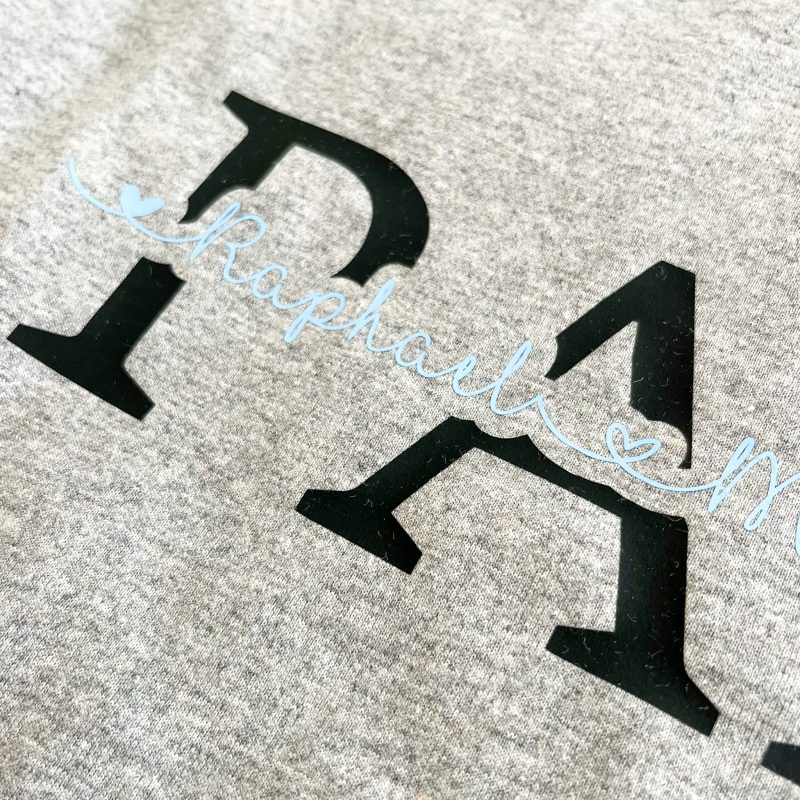 Graues Shirt mit dem Aufdruck Papa in schwarz und Namen der Kinder in hellblau